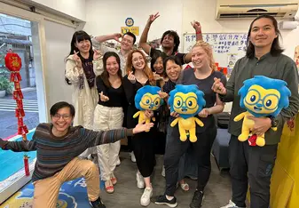 group of students standing in front of a whiteboard holding plushies