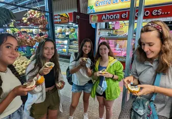 A group of girls hold a fruit and smile at the camera.