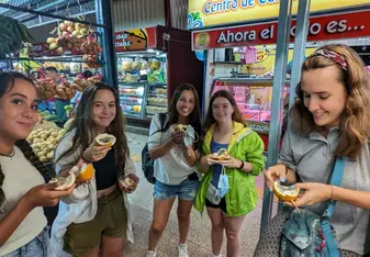 A group of girls hold a fruit and smile at the camera.