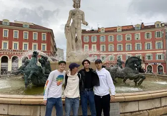 Friends stand in front of a fountain in Italy.