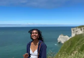 Student sitting on a hill overlooking a body of water, enjoying all that France has to offer