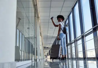 A woman stands in an aiport and waves.