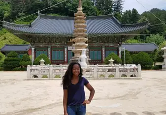 A young woman poses in front of a temple in South Korea.