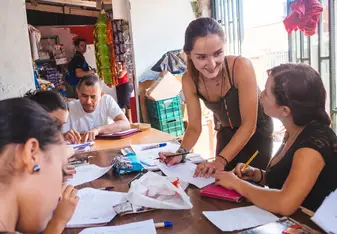 A teacher works with a group of adults at a table.