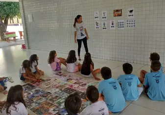 A teacher stands in front of a class of young children.