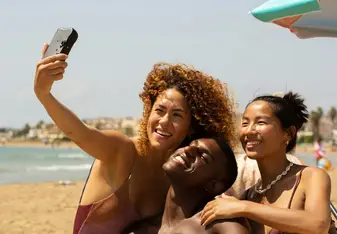 A group of friends take a selfie on the beach.