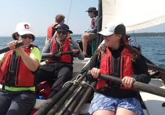 Students in a sailboat maneuvering oars.