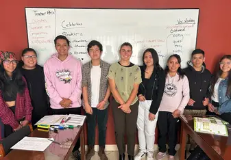A teacher and their students near the whiteboard in class