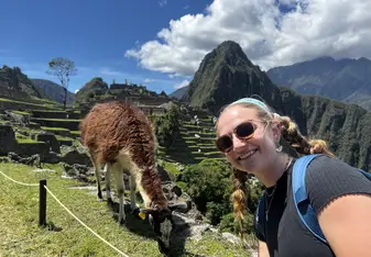 Girl smiling and taking a selfie in front of a llama at Machu Picchu 