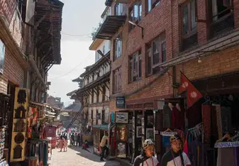 A traditional street scene in Kathmandu with local shops and two people in traditional attire.