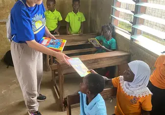 Volunteer handing book to student