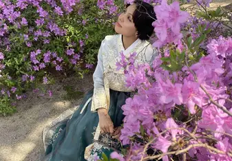 Marlene in traditional South Korean clothing beneath purple flowers