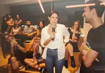 Candida speaking into a microphone while a student smiles and listens