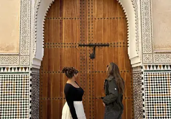 Two students standing in front of a wooden, carved door in the Medina