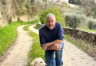 Lorenzo smiles happily beside his dog in the countryside
