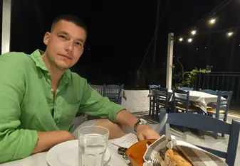Dimitrios smiling at the camera while enjoying his evening meal