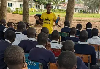 Opondo stands in front of young people giving a speech