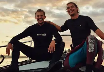 Eric and his fellow instructor smile for a photo with a sunset in the background