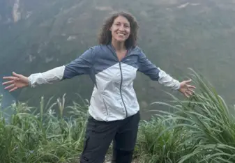 Maggie stands with arms wide above a river canyon