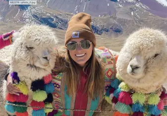 Maggie stands for a photo between two Alpacas 