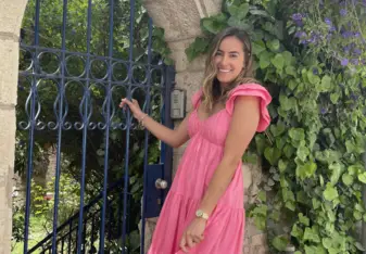 Maggie poses for a photo in front an archway and beautiful greenery