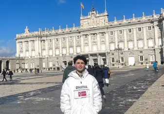 Jack stands in front of a beautiful European style building for a photo