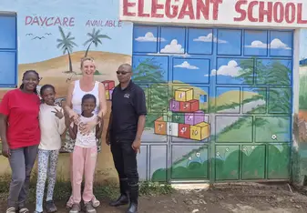 Nicole smiles in front of school with students