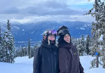 Two people on a snowy mountain with ski gear on