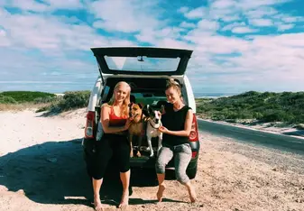 Two people in the car with dogs on a sunny day