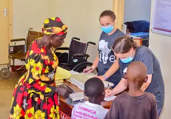 Volunteers and local staff documenting patient information inside the Maisha clinic during a medical care day