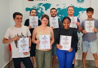 TEFL trainees holding certificates during graduation ceremony in training classroom.