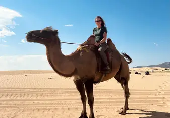 Cawston image of woman on top of camel in the desert