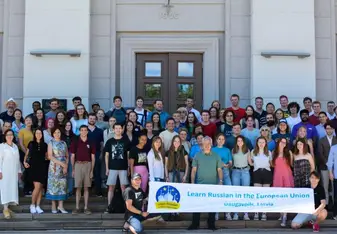 group of students and teachers in front of colorful banner
