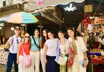 Students smiling in front of a market