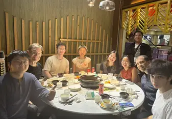 Group of people around a round dinner table smiling 
