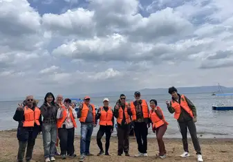 Group of people in orange life jackets on a shore smiling