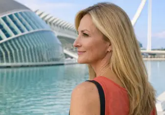 Blonde woman looking across water near a bridge