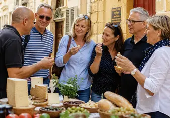 Mature students attending a food tour in Valetta, Malta. Trying food from the market.