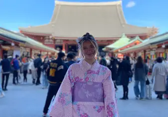 Smiling intern in kimono standing in front of a temple