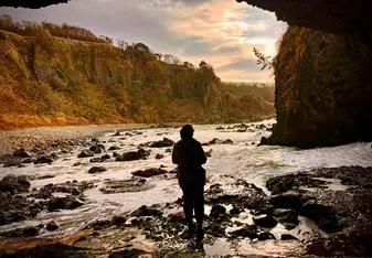 Maddie in a setting by a river in a canyon at sunset