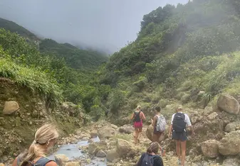 Sea|mester students hike a rocky trail through misty green mountains in the Caribbean