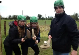 three students learning the sport of hurling