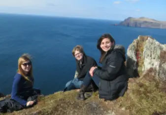 three students sitting on a cliff dingle peninsula ireland