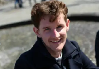 A young man standing in front of the wall.