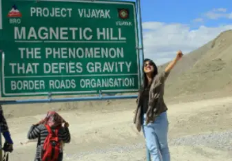 woman by the magnetic hill sign project vijayak