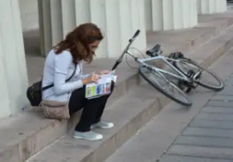 woman sitting on sidewalk looking at a map