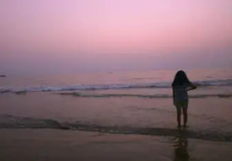 A young woman standing by the water.