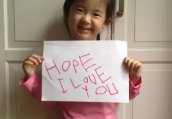 little girl holding cute "i love you" sign