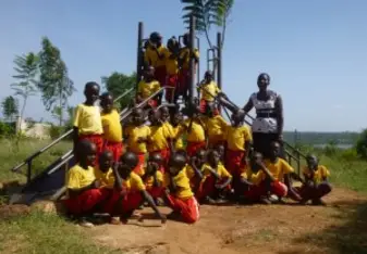 Children gathered up for a group picture with their teacher. 