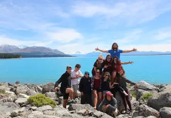 group of people standing on rocks in front of ocean